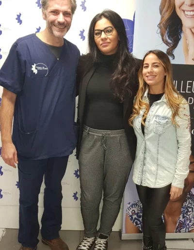 Trois personnes posent devant une affiche médicale.