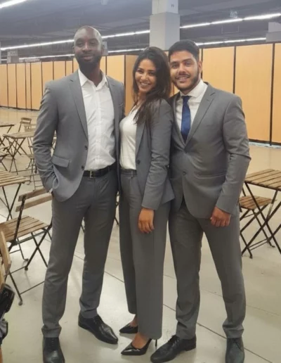 Trois personnes en costumes gris posent ensemble