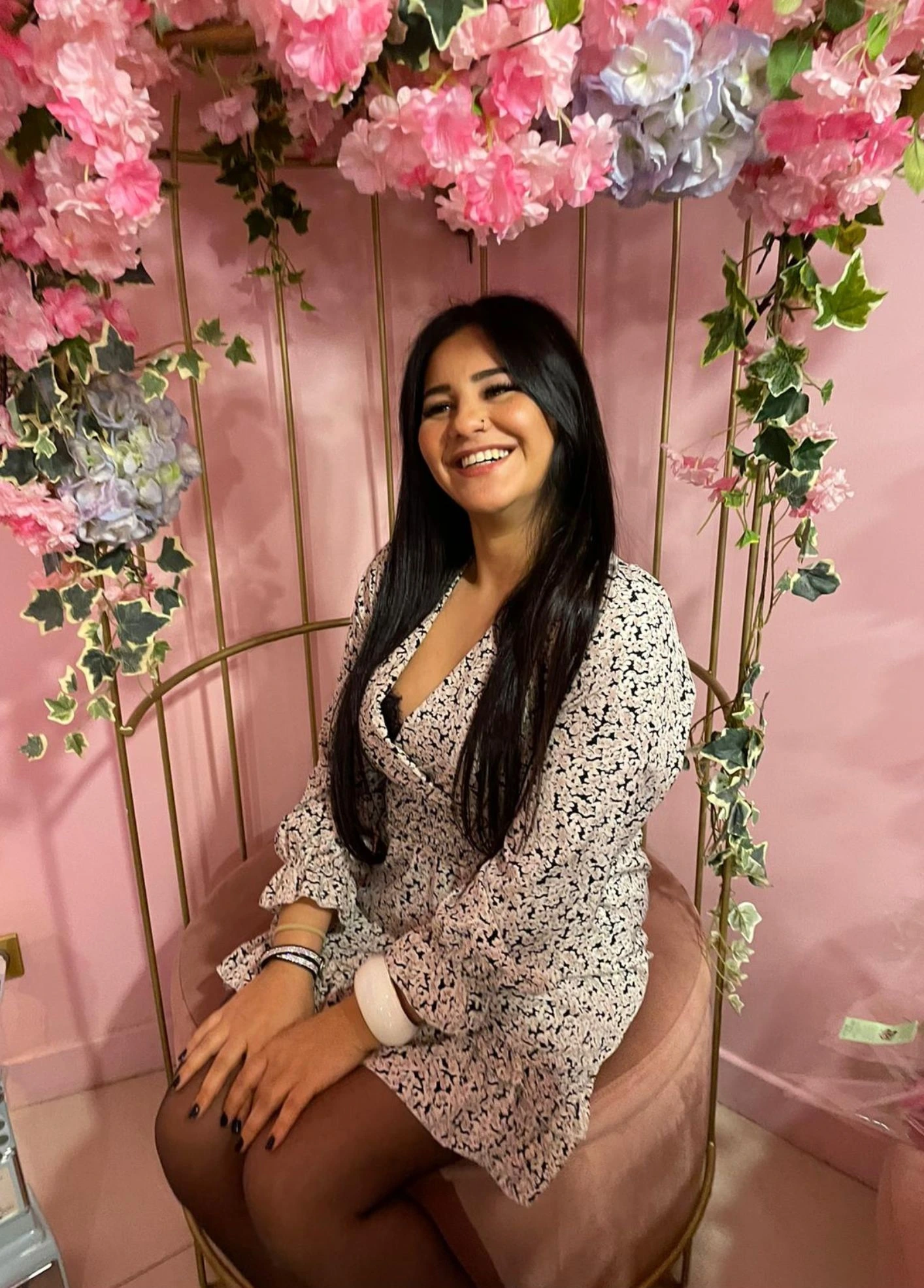 Femme souriante assise sous des fleurs roses